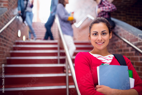 Female holding books with students on stairs in college
