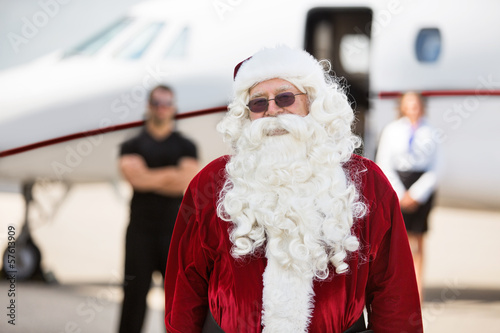 Man In Santa Costume Standing Against Private Jet
