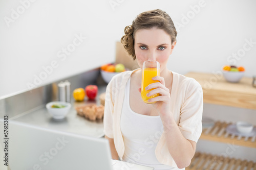 Cute woman drinking a glass of orange juice sitting in her kitch