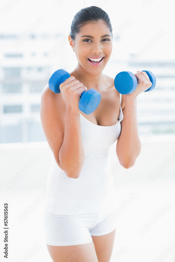 Happy toned brunette holding dumbbells Happy toned brunette holding dumbbells