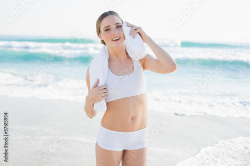 Smiling slender woman touching face with white towel
