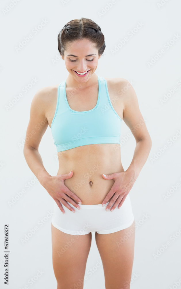 Smiling fit woman in sportswear with hands on belly Smiling fit woman in sportswear with hands on belly