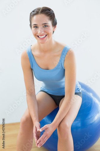 Smiling fit woman sitting on exercise ball