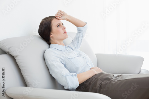 Serious well dressed woman sitting on sofa
