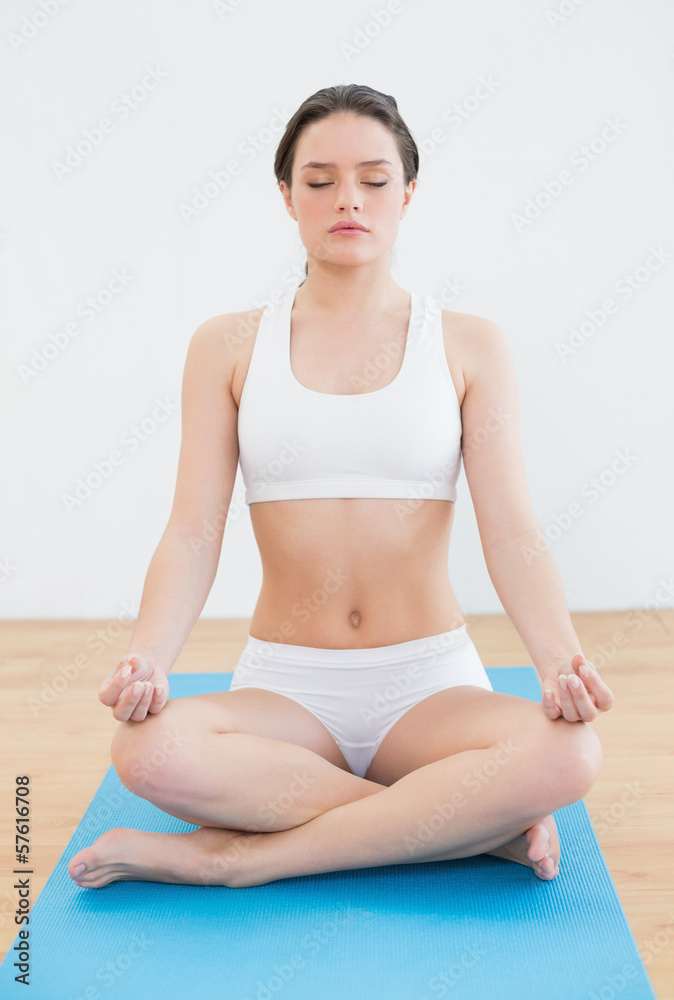 Toned woman sitting in lotus pose with eyes closed