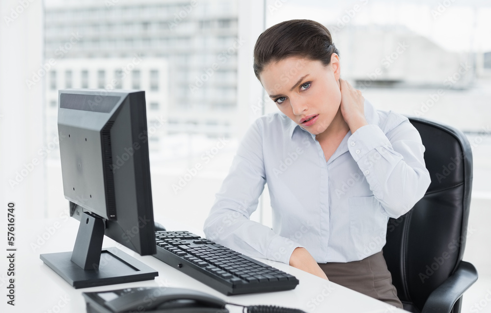 Businesswoman with neck pain sitting at office Businesswoman with neck pain sitting at office