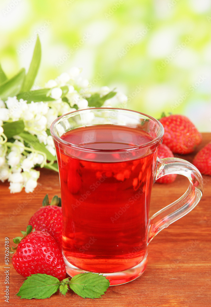 Delicious strawberry tea on table on bright background Delicious strawberry tea on table on bright background