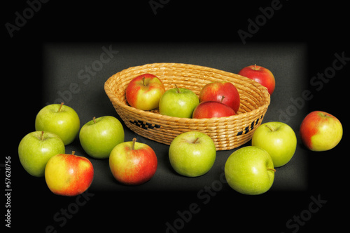 Red and green apples in a basket on dark background