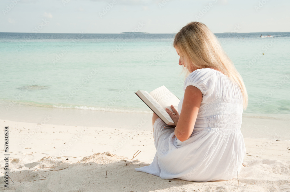 blond woman on beach with a book