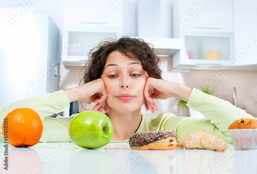 Dieting concept. Young Woman choosing between Fruits and Sweets