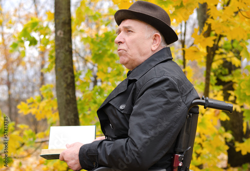 Pensive man reading on park in autumn