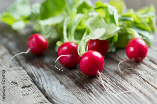 red radish with leaves on wooden table - ravanelli