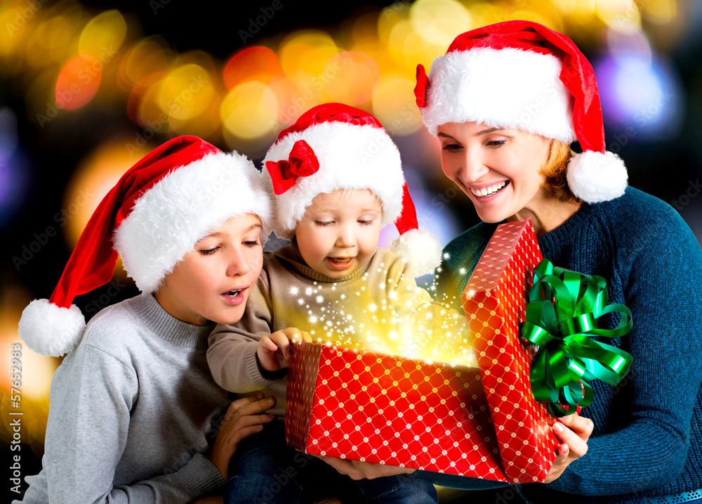 Mother with children opens the box with gifts on the christmas h Mother with children opens the box with gifts on the christmas h