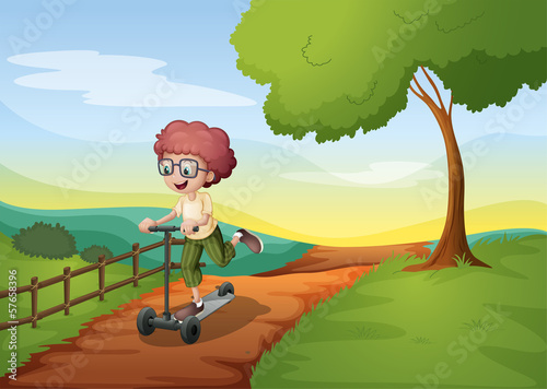 A smiling young boy riding with his scooter