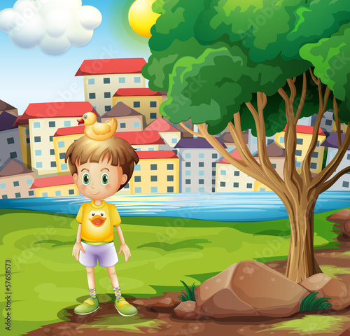 A boy with a rubber duck above his head standing near the tree