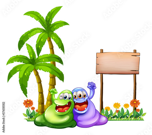 Two monsters having fun in front of the empty wooden signboard