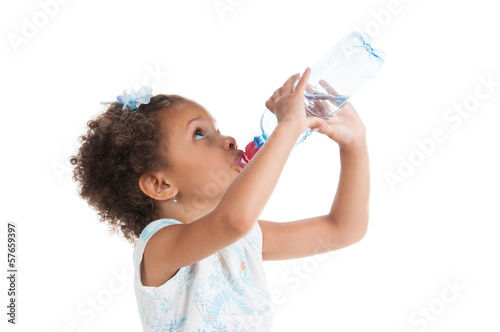 The little girl drinks water from a bottle.
