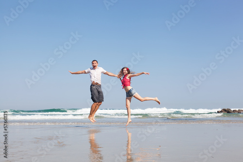 young loving couple joyfully jumps on a tropical beach