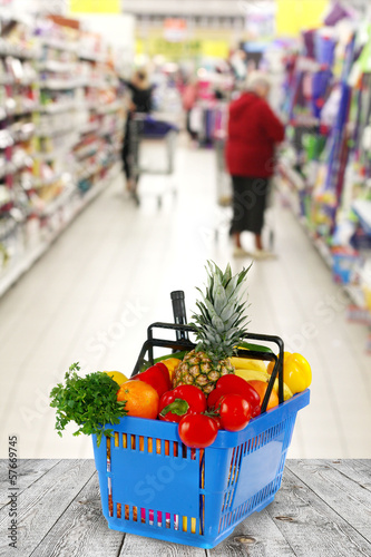 Shopping basket with groceries on shop of background