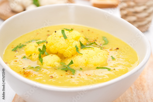 cauliflower soup with curry and cream in a bowl, close-up