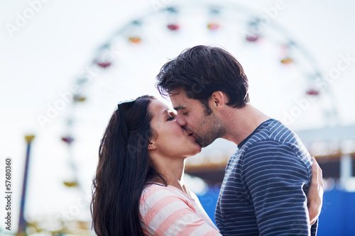 romantic couple kissing in front of santa monica ferris wheel