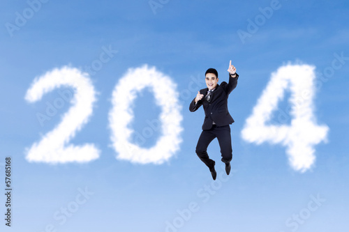 Happy businessman jumping with clouds of 2014