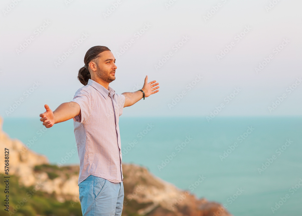 man stands on a cliff near the sea at sunset man stands on a cliff near the sea at sunset