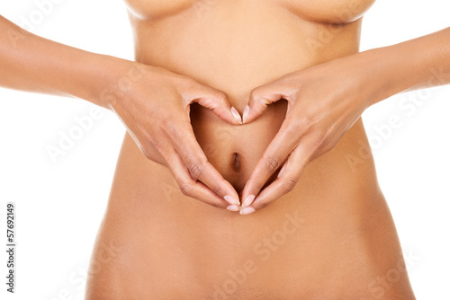 Sexy naked young woman is making heart shape with her hands on h