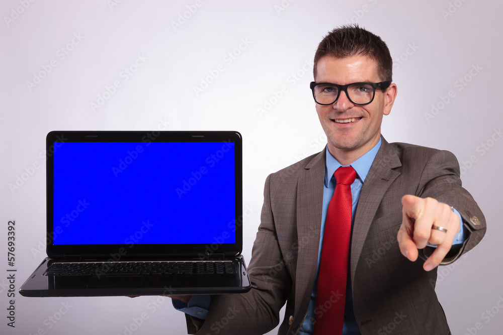 young business man presents a laptop and points at you young business man presents a laptop and points at you