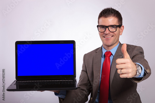 young business man presents laptop with thumb up