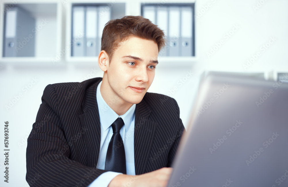 Young businessman working on laptop in office
