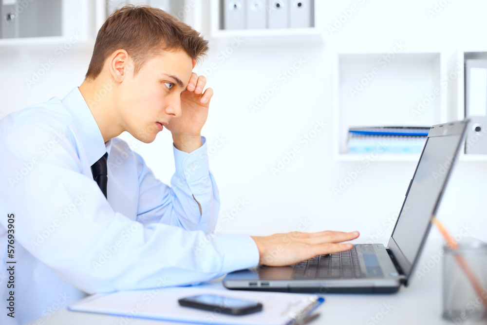 Young businessman working on laptop in office Young businessman working on laptop in office