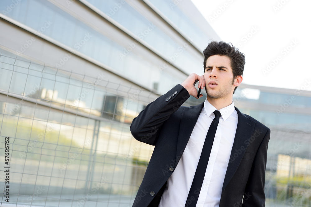 Attractive young businessman on the phone in an office building
