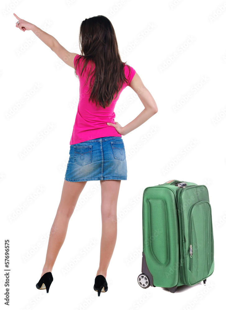 Beautiful young woman in dress traveling with suitcas and pointi Beautiful young woman in dress traveling with suitcas and pointi