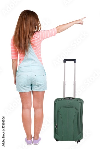 Back view of traveling pointing woman with suitcase