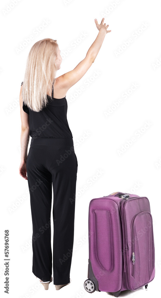 Back view of young blonde woman traveling with suitcas and point Back view of young blonde woman traveling with suitcas and point