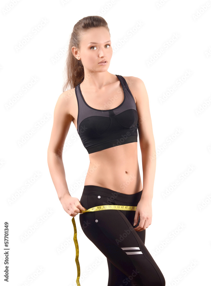 Fit girl measuring her hips with a measuring tape in inch. Fit girl measuring her hips with a measuring tape in inch.