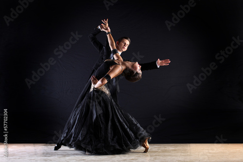Latino dancers in ballroom against on black background