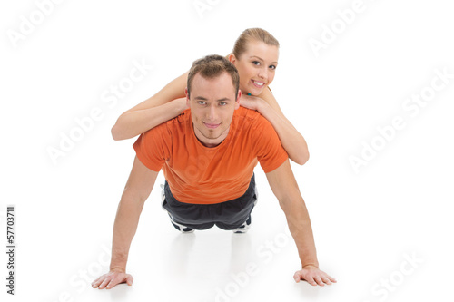 Handsome man exercising with beautiful woman on his back.