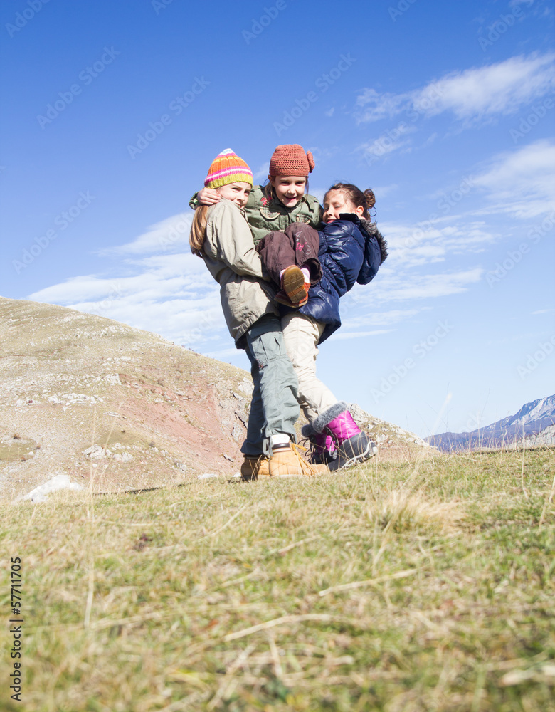 Three kids running and jumping on the top of the hill