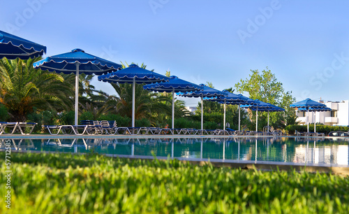 Blue umbrellas in a row near swimming pool