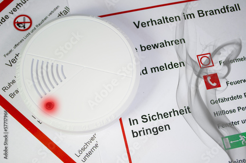 Rauchmelder mit Bauplan und Haus und Rauch