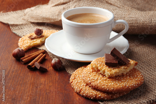 Cup of tasty coffee with tasty cookies, on wooden background