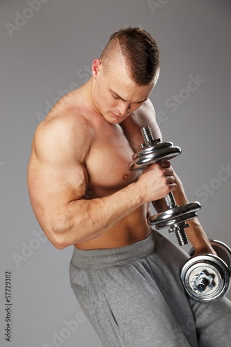 Handsome young muscular man exercising with dumbbells
