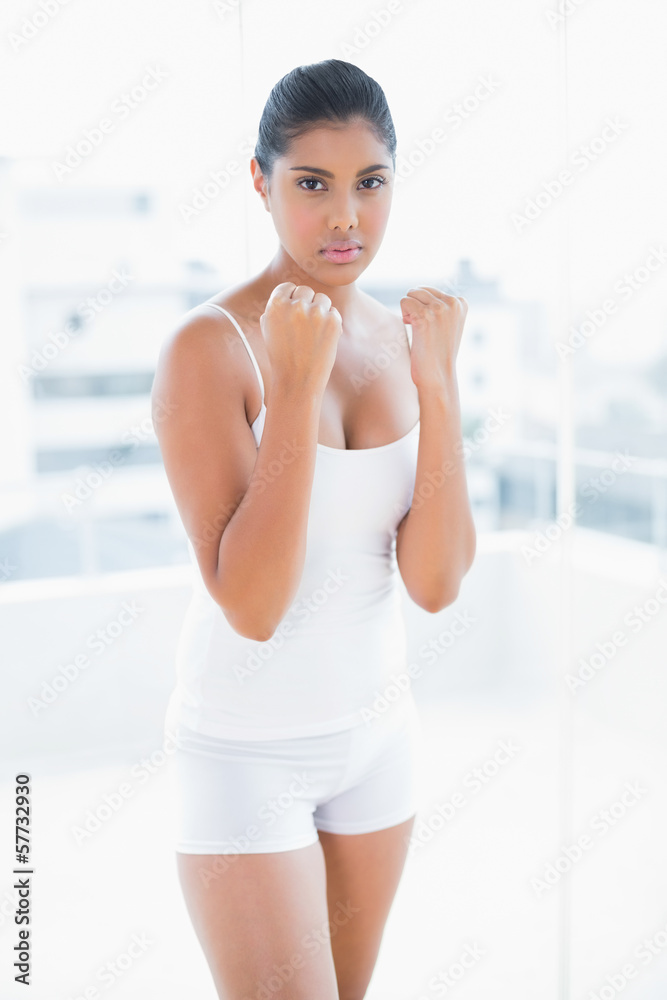 Serious toned brunette standing with lifted fists