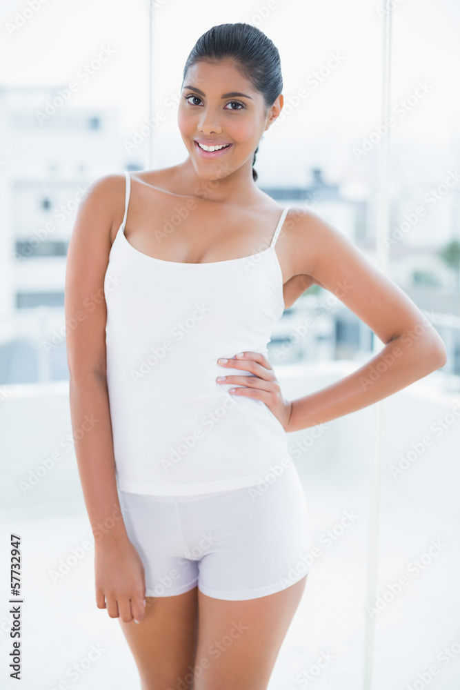 Happy toned brunette standing with hand on hips Happy toned brunette standing with hand on hips