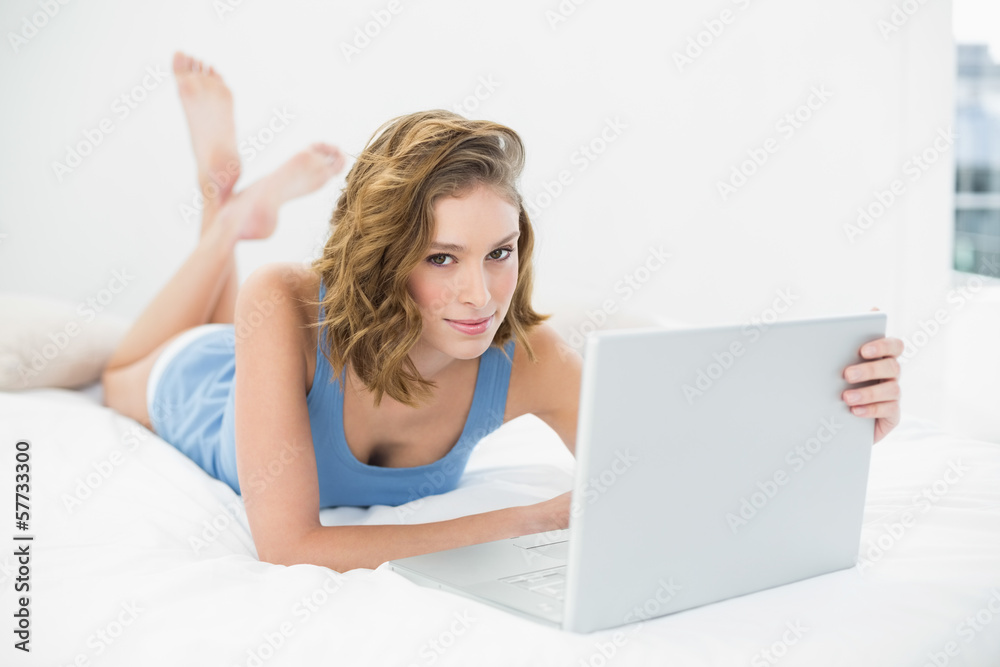 Attractive calm woman using her white notebook looking at camera Attractive calm woman using her white notebook looking at camera