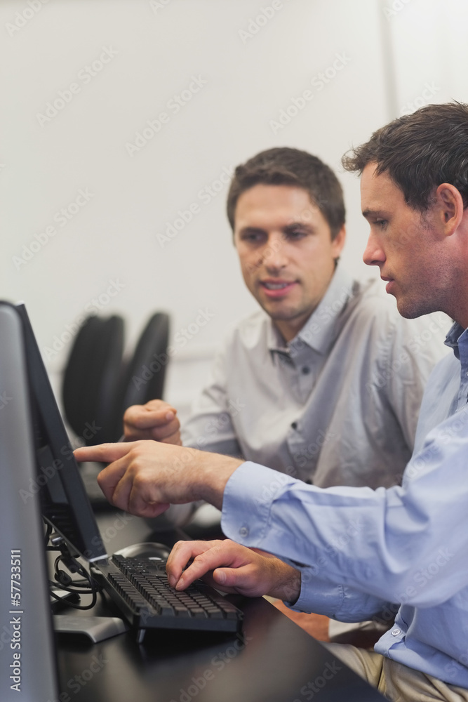 Two mature men talking while sitting in front of computer Two mature men talking while sitting in front of computer