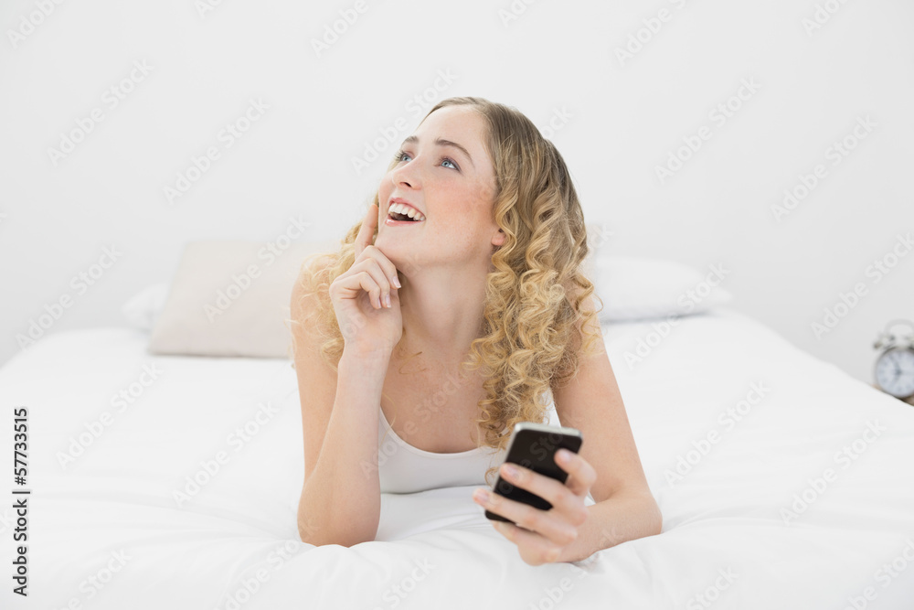 Pretty day dreaming blonde lying on bed using smartphone Pretty day dreaming blonde lying on bed using smartphone