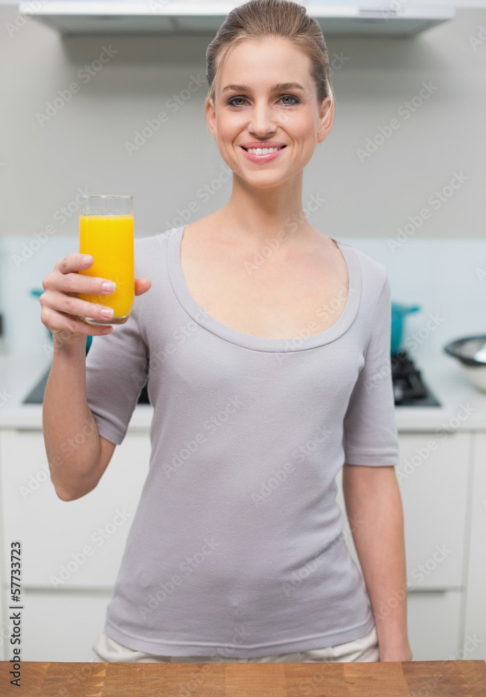 Smiling gorgeous model looking at camera holding orange juice Smiling gorgeous model looking at camera holding orange juice
